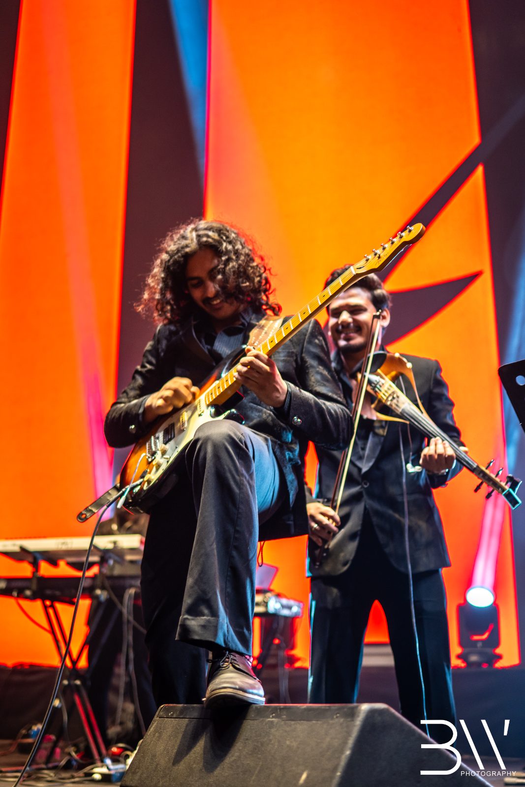 Two band members against an orange backdrop